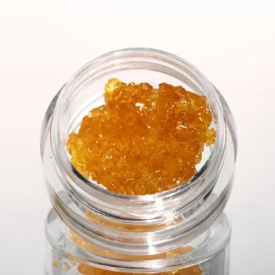 close-up of golden cannabis concentrate gods green crack diamonds inside a clear glass container